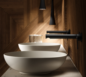 Ein modernes Badezimmer mit zwei runden weißen Waschbecken, schwarzen Wandarmaturen und strukturierten Holzwänden, sanft beleuchtet von Pendelleuchten.